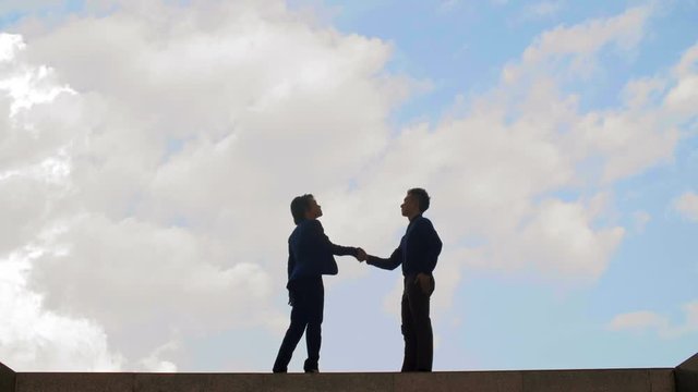 Wide shot of male and female Asian business people going towards each other, shaking hands and thus making a deal