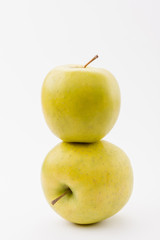 stack of two ripe golden delicious apples on white background