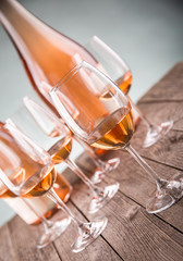 Glasses and bottles with fine rose wine on rustic old wooden table selective focus