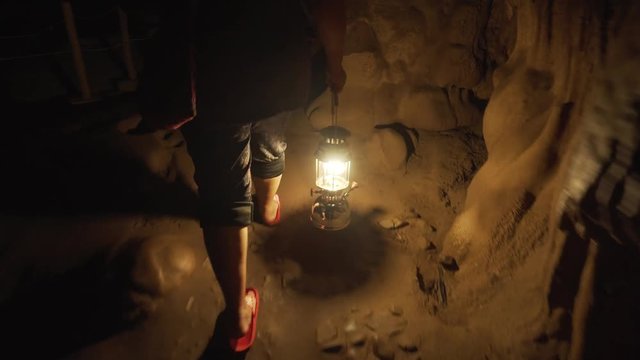 A woman with a kerosene lamp (lantern) goes inside a cave, climbs stone steps in the dark. Lod Cave. Thailand. Chiang Mai.