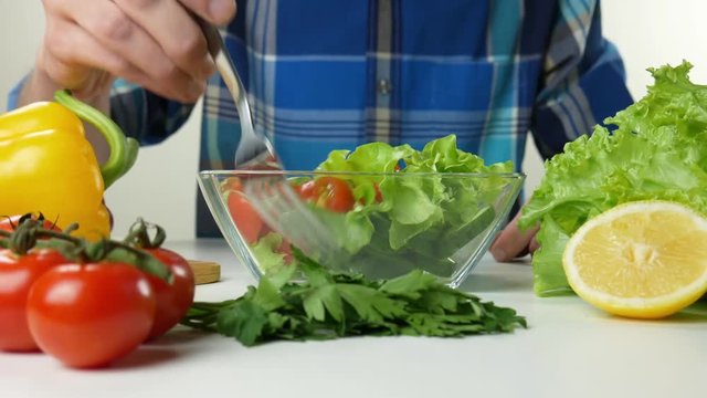 Healthy food. Vegetarian food. Young man coocking vegetable salad observing diet and counting calories wellness
