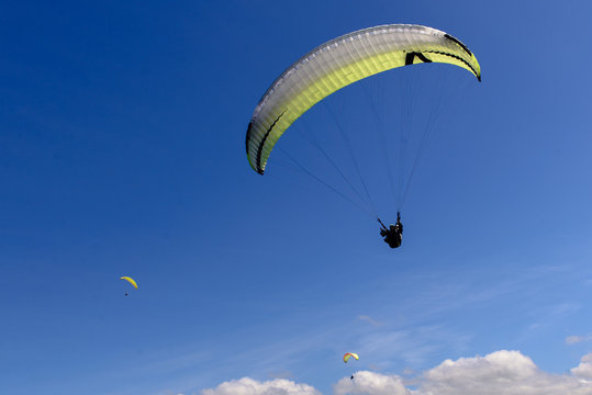 Paragliders against cloudy sky