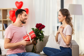 valentines day, couple, relationships and people concept - happy man giving woman flowers and...
