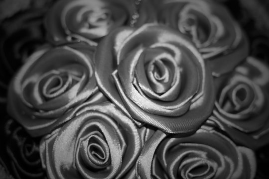 black and white concept, texture of silk fabric in black color folded in the form of a rose. Blur background 