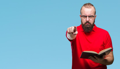Young hipster man wearing glasses and reading a book over isolated background pointing with finger...