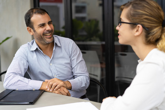 Cheerful mid adult hr manager having interview with candidate. Caucasian male manager talking to female client. Job interview or meeting concept