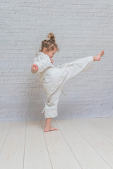 girl, a child in a kimono on karate training works out blows and greeting