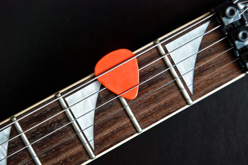 electric guitar fingerboard and orange pick
