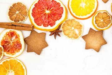 Border of Dried slices of various citrus fruits gingerbread and spices on white background with copyspace