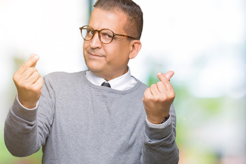 Middle age bussines arab man wearing glasses over isolated background Doing money gesture with...