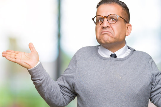 Middle age bussines arab man wearing glasses over isolated background clueless and confused expression with arms and hands raised. Doubt concept.