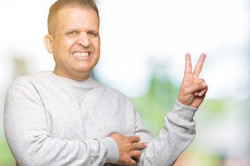 Middle age arab man wearing sport sweatshirt over isolated background smiling with happy face winking at the camera doing victory sign. Number two.