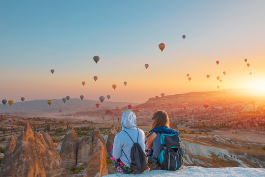 Hot air balloon flying over spectacular Cappadocia - Girls watching the hot air balloon at the hill of Cappadocia
