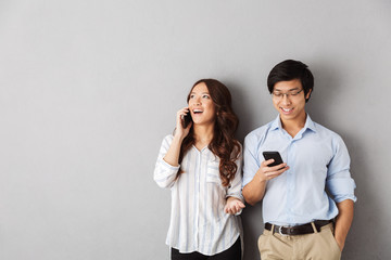 Happy asian couple standing isolated over gray
