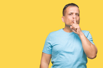 Middle age arab man wearing blue t-shirt over isolated background asking to be quiet with finger on lips. Silence and secret concept.