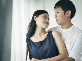 Romantic Asian couple hug and kissing near window at home, lifestyle concept.