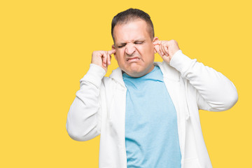 Middle age arab man wearing sweatshirt over isolated background covering ears with fingers with annoyed expression for the noise of loud music. Deaf concept.