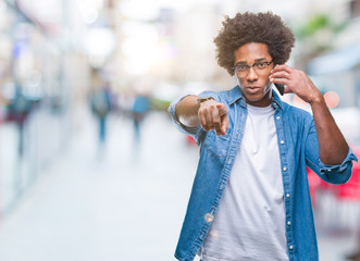 Afro american man talking on the phone over isolated background pointing with finger to the camera and to you, hand sign, positive and confident gesture from the front