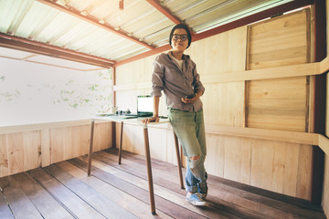 Professional freelancer 25-30 year is smiling looking digital camera  Personal enjoying at wood house office small with desk and vintage bicycle Instagram style filter photo