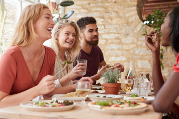 Four young adult friends eating in a restaurant, close up