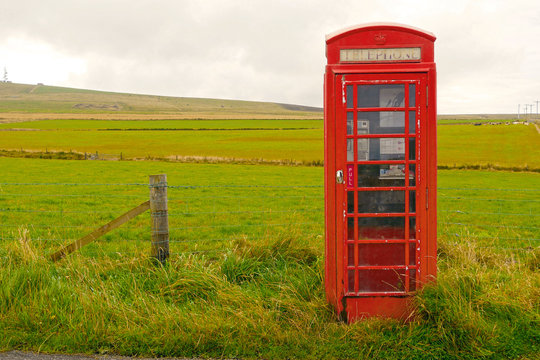 Kirkwall, Orkney Islands / United Kingdom - August 2014: Lonely red phone booth in a rural scenery.