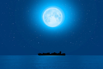 Silhouette of the cargo ship with super full moon (moonrise) 