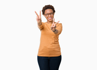 Young beautiful african american woman wearing glasses over isolated background smiling looking to the camera showing fingers doing victory sign. Number two.