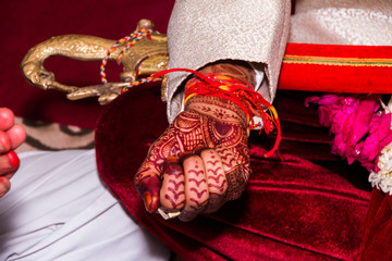 close up of a groom's wrist holding auspicious rice grains as a part of wedding ritual in Indian...