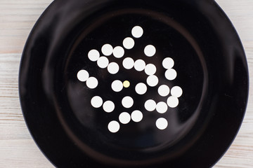 abuse of medical drugs - many tablets lying on a black plate, top view