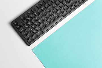 Computer keyboard on a turquoise paper background