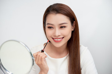 Young beautiful woman making make-up near mirror,sitting at the desk