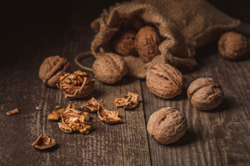 close up view of walnuts in sack on wooden background