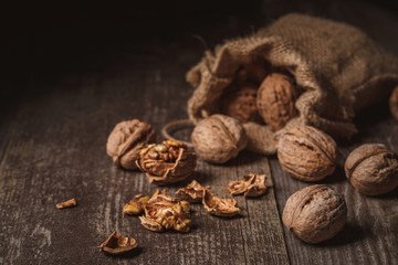 close up view of walnuts in sack on wooden background