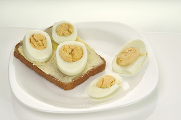 Fototapeta na wymiar Sandwich with bread, butter, egg and cheese on a white plate and white background, close-up