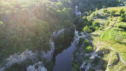 Aerial shot of curvy river stretching between rugged banks with sedge in summer