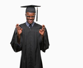 Young graduated african american man over isolated background smiling crossing fingers with hope and eyes closed. Luck and superstitious concept.