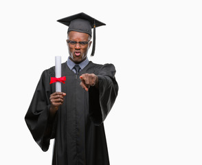 Young graduated african american man holding degree over isolated background pointing with finger to the camera and to you, hand sign, positive and confident gesture from the front