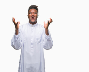 Fototapeta premium Young arabic african man wearing traditional djellaba over isolated background celebrating mad and crazy for success with arms raised and closed eyes screaming excited. Winner concept