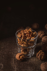 close up view of shelled walnuts in glass on wooden surface