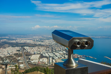 Closeup view of coin operated binocular viewer for looking in details at beautiful summer cityscape landscape. Antalya, Turkey. Happy summer holidays and sightseeing concept. Horizontal photography.