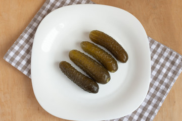 Pickle cucumbers on white plate top view. Fermented vegetables. 