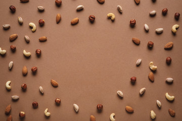 Fototapeta na wymiar full frame of various nuts arranged on brown backdrop with empty space in middle