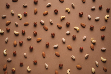 full frame of various nuts arranged on brown backdrop