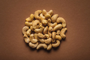 top view of pile of cashew nuts on brown background