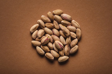 top view of pile of pistachio nuts on brown backdrop
