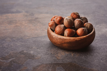 close up view of shelled hazelnuts in wooden bowl on grey tabletop