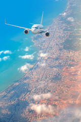 Obraz premium An airplane is flying over low clouds and city with blue sea 