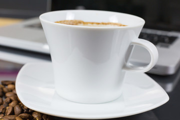 Coffee cup on a job desk with laptop