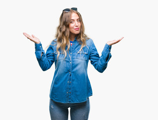 Beautiful young blonde woman wearing sunglasses over isolated background clueless and confused...