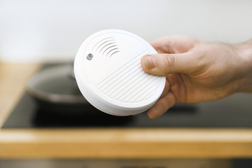 Man holding smoke detector in the kitchen.